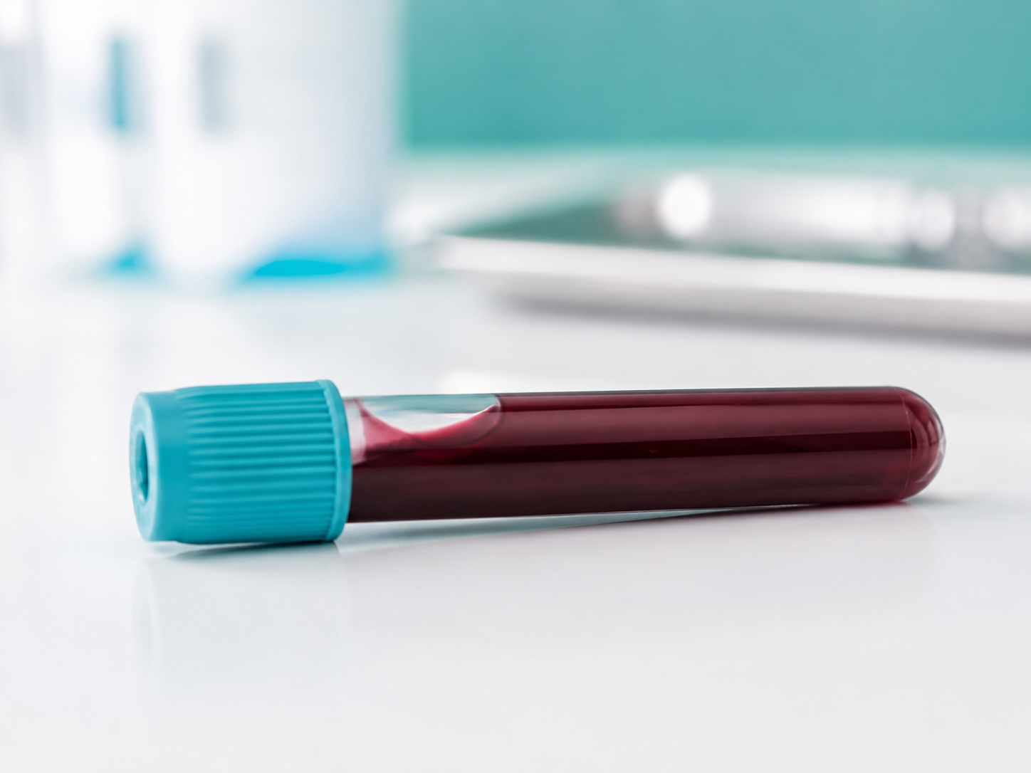 Tubo de análisis de sangre sobre superficie clínica blanca, representando el diagnóstico de triglicéridos altos mediante analítica